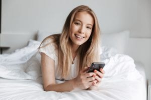 Cheerful beautiful young woman lies in bed.