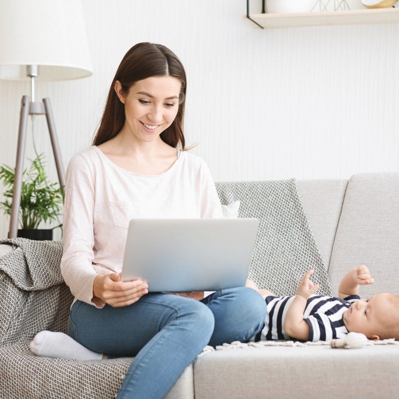 Beautiful young mother reading baby blog on laptop